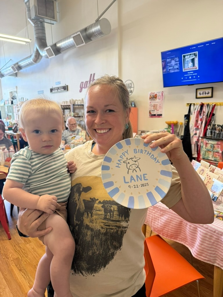 Woman holding toddler displaying birthday plate