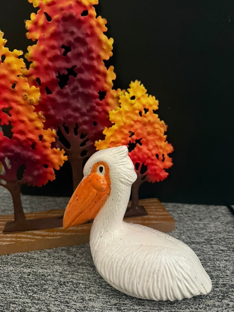 White pelican figurine with autumn trees