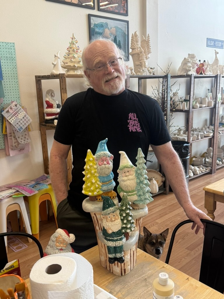 Man displaying carved wooden Santa figurines