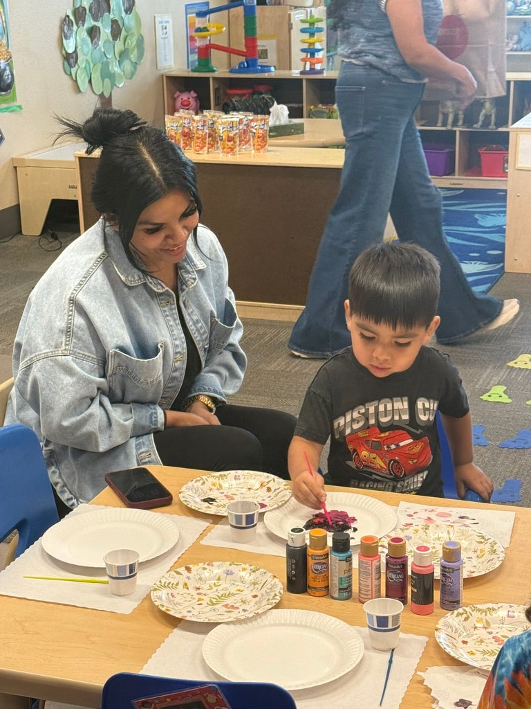Teacher and child decorating pottery together